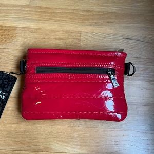 A Red Crossover bag with multiple black straps and can wear multiple ways.